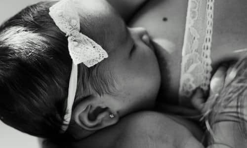 little baby girl breastfeeding with bow